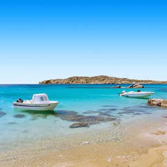 Helderblauwe zee met boot aan de kust van Mykonos, Griekenland